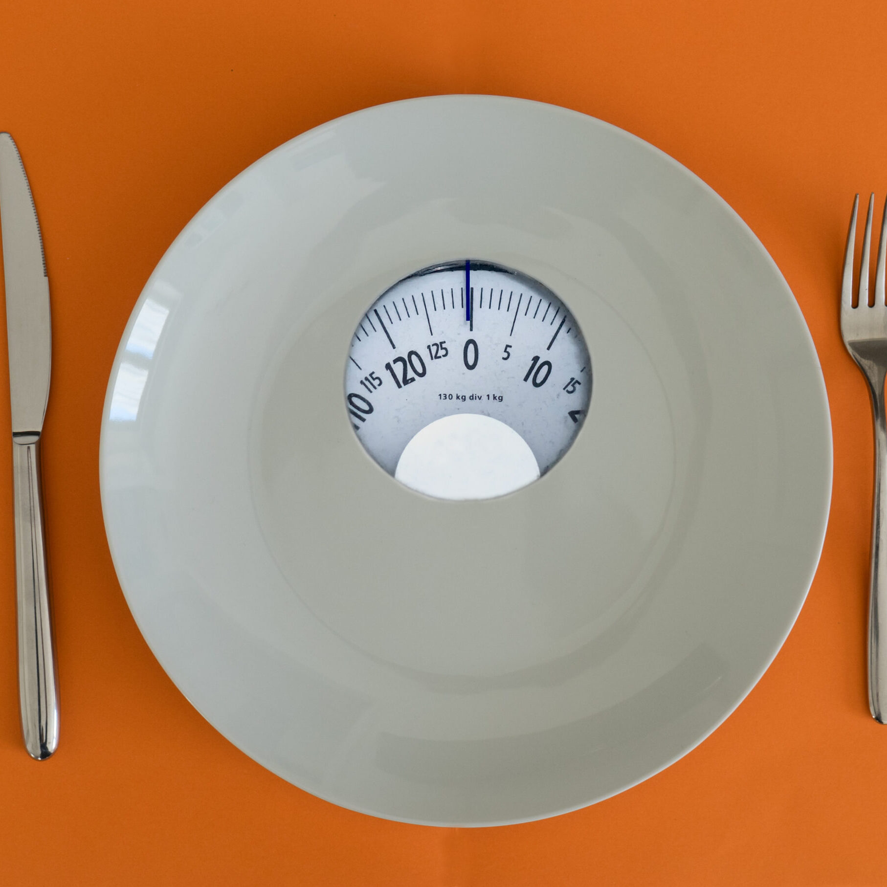 White plate with weight scale. Anorexia and eating disorder concept.